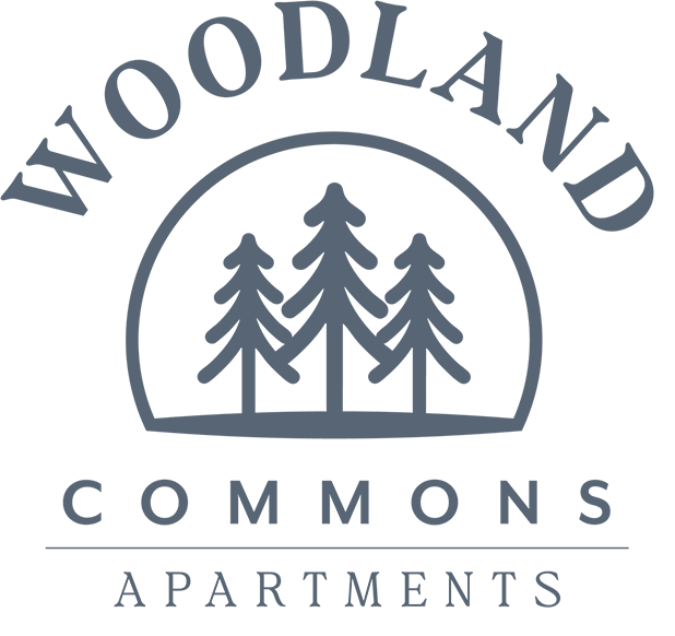The image is a logo for Woodland Commons Apartments.